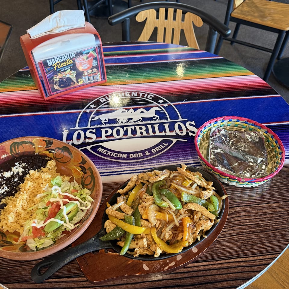 Mexican fajitas, rice, beans, and salad served on a colorful Los Potrillos Mexican Bar & Grill table.